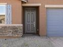 A close-up view of the front entry featuring a dark door, stone accents and gray trim at 8657 W Warner St, Tolleson, AZ 85353