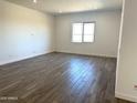 Bright living room with wood-look floors, a large window, and neutral paint at 43513 N Wollemi St, Queen Creek, AZ 85140
