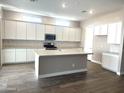 Modern kitchen boasts white cabinets, a center island with a sink, and stainless steel appliances at 43429 N Wollemi St, Queen Creek, AZ 85140