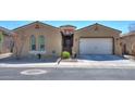 Charming, tan single-story home featuring a two-car garage, arched windows, and a well-manicured yard at 18169 W Cactus Flower W Dr, Goodyear, AZ 85338