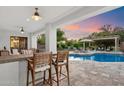 Covered outdoor bar with seating overlooks the pool and patio area for relaxed entertaining at 744 E County Down Dr, Chandler, AZ 85249