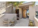 Front entrance with wood door and two wicker chairs at 9250 E Whitethorn Cir, Scottsdale, AZ 85266