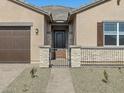 Warm and inviting front entrance with a gated courtyard, stone accents, and a covered porch at 17648 W Pierson St, Goodyear, AZ 85395