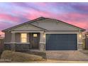 A dusk shot of this single-story home showcases the stonework, garage and desert landscaping at 17737 W Elm St, Goodyear, AZ 85395