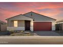 Single-story home at dusk, showcasing a well-kept exterior with neutral tones and a brick driveway at 17743 W Elm St, Goodyear, AZ 85395