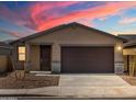 Beautiful single-story home with a two-car garage against a vibrant sunset backdrop at 9120 N 174Th Ln, Waddell, AZ 85355