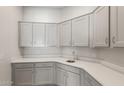 Well-lit laundry room featuring white cabinets, modern countertops, and a stainless steel sink at 7736 W Mockingbird Way, Florence, AZ 85132