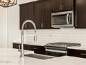 Close-up of kitchen showcasing stainless steel appliances, dark wood cabinetry, and a stylish faucet at 22507 W Pontiac Dr, Surprise, AZ 85387