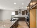 Spacious kitchen with dark wood cabinets, granite counters, and stainless steel appliances at 17867 W Encinas Ln, Goodyear, AZ 85338