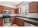 L-shaped kitchen with dark wood cabinets, granite counters, and stainless steel appliances at 2315 N 52Nd St # 120, Phoenix, AZ 85008