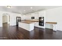 Spacious kitchen featuring white cabinets, an island, stainless appliances, and dark hardwood floors at 2542 N Riley Rd, Buckeye, AZ 85396