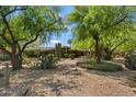 Charming single-story home featuring desert landscaping with mature trees, cacti, and a gravel yard for easy maintenance at 4531 E Quartz Mountain Rd, Paradise Valley, AZ 85253