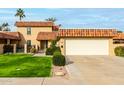 Tan two-story home with terracotta roof and lush lawn at 9734 N 105Th Dr, Sun City, AZ 85351