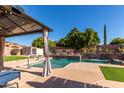 Inviting backyard oasis with a sparkling pool, waterfall feature, and covered patio at 3121 S Verde Cir, Mesa, AZ 85212