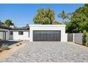 Attached two-car garage with gray door and white brick exterior; modern landscaping, wide gray brick driveway at 342 E Orangewood Ave, Phoenix, AZ 85020