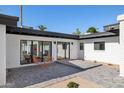Outdoor patio area with modern seating, brick pavers, sleek black trim, and view to manicured greenery at 342 E Orangewood Ave, Phoenix, AZ 85020