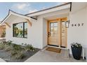 Inviting exterior featuring a light-colored facade, wood front door, and landscaping at 8437 E San Miguel Ave, Scottsdale, AZ 85250