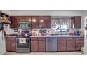 Galley style kitchen with dark wood cabinets and stainless steel appliances at 5625 N 67Th Dr, Glendale, AZ 85303