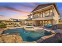 Stunning backyard oasis with a rock-rimmed pool, spa, covered patio, and manicured landscaping for relaxing outdoors at 3428 N Park St, Buckeye, AZ 85396
