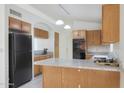 Galley kitchen with wood cabinets, granite countertops, and black appliances at 19822 N 43Rd Dr, Glendale, AZ 85308