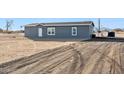 Rear view of a gray manufactured home with a large undeveloped lot at 53275 W Adele Rd, Maricopa, AZ 85139