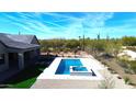 Aerial view of a backyard featuring a modern pool, spa, artificial turf and desert landscaping at 8714 E Tether Trl, Scottsdale, AZ 85255