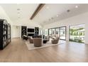Bright living room featuring a beamed ceiling, light wood floors, and sliding glass doors with views of the pool at 6040 E Lafayette Blvd, Scottsdale, AZ 85251