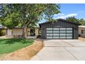 Mid-century home with a dark gray garage and a tree in front at 6733 N 14Th St, Phoenix, AZ 85014