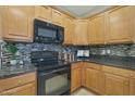 Kitchen with wood cabinets, granite counters, and black appliances at 13520 W Junipero Dr, Sun City West, AZ 85375