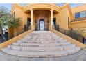 Close up of the grand entryway of the home with stone accents, pillars and steps to the black iron door at 16149 E Thistle Dr, Fountain Hills, AZ 85268