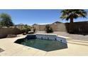 Backyard pool featuring tiled trim, stone landscaping, privacy wall and mature palm trees under a clear blue sky at 22814 W Cantilever St, Buckeye, AZ 85326
