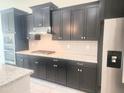 Modern kitchen featuring granite counters, stainless appliances, gas cooktop and stylish dark cabinetry at 4866 N 185Th Dr, Goodyear, AZ 85395