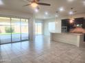Open-concept living area with tile flooring, bar seating and access to a bright and spacious kitchen at 4866 N 185Th Dr, Goodyear, AZ 85395