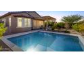 Inviting backyard oasis with sparkling pool, covered patio, and desert landscaping at 18076 W Nighthawk Way, Goodyear, AZ 85338