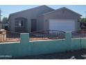 Newly constructed home with a gray exterior, attached garage, and red iron fence at 3021 W Almeria Rd, Phoenix, AZ 85009