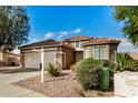 Tan house with a two-car garage, stone accents, and desert landscaping at 13348 W Calavar Cir, Surprise, AZ 85379