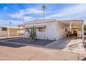 White manufactured home with covered parking and mature landscaping at 201 S Greenfield Rd # 142, Mesa, AZ 85206