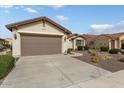 Front view of a beige house with a two-car garage and drought-tolerant landscaping at 26180 W Firehawk Dr, Buckeye, AZ 85396