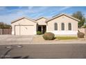 Tan house with a three-car garage, landscaping, and a large front yard at 3410 N 131St Ln, Litchfield Park, AZ 85340