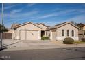Tan house with a three-car garage and desert landscaping at 3410 N 131St Ln, Litchfield Park, AZ 85340