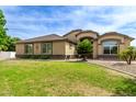 House exterior showcasing a tan facade, manicured lawn, and palm trees at 20811 E Excelsior Ave, Queen Creek, AZ 85142