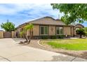 House exterior with tan walls, tile roof, and lush green landscaping at 20811 E Excelsior Ave, Queen Creek, AZ 85142