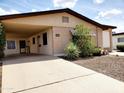 View of the home's exterior showcasing the carport, desert landscaping, and a well-kept lawn at 2233 N Middlecoff Dr, Mesa, AZ 85215