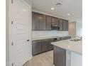 Well-lit kitchen with gray cabinetry, white backsplash, and stainless steel appliances at 24177 W Hilton Ave, Buckeye, AZ 85326