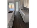 Bright kitchen design with white cabinets, gray subway tile, an island with stainless steel sink, and hard surface floors at 31277 N 130Th Ave, Peoria, AZ 85383