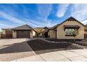 Beautiful tan house with a brown roof, brick driveway, and nicely landscaped yard at 7130 W Rowel Rd, Peoria, AZ 85383