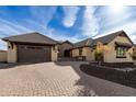 Tan house with brown roof and brick driveway; nicely landscaped at 7130 W Rowel Rd, Peoria, AZ 85383