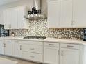 Modern kitchen with white cabinets, gas cooktop, and mosaic backsplash at 13172 N 174Th Dr, Surprise, AZ 85388