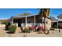 Tan manufactured home with covered porch, landscaping, and stairs at 2233 E Behrend Dr # 24, Phoenix, AZ 85024