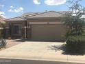 Tan house with a two-car garage and drought-tolerant landscaping at 45091 W Gavilan Dr, Maricopa, AZ 85139
